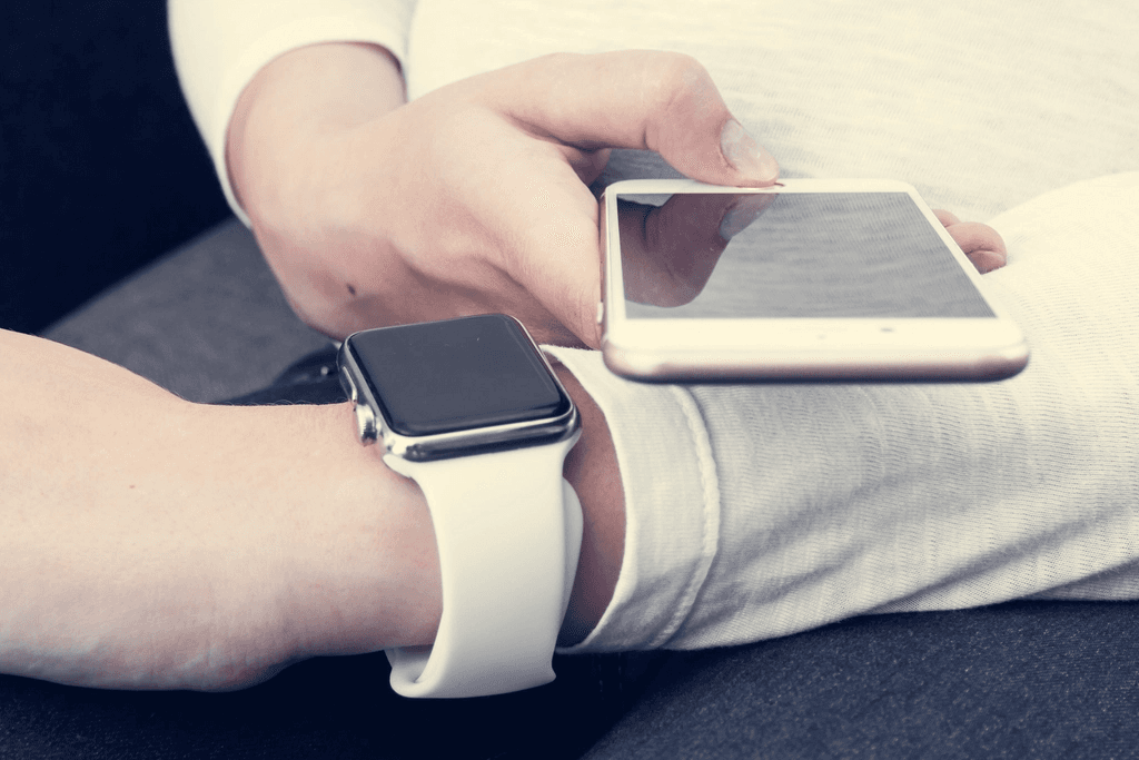 Elinde telefon tutan akıllı saatli kişi